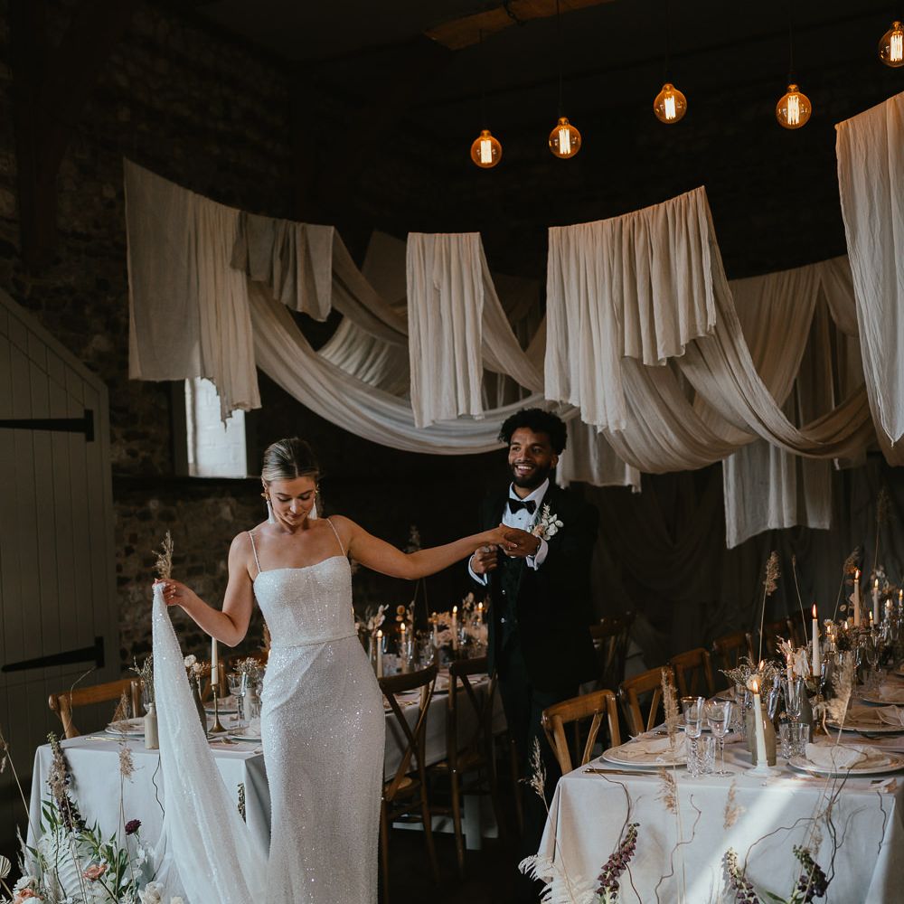Modern luxury wedding reception with drapes, festoon lights and black tie wedding fashion 