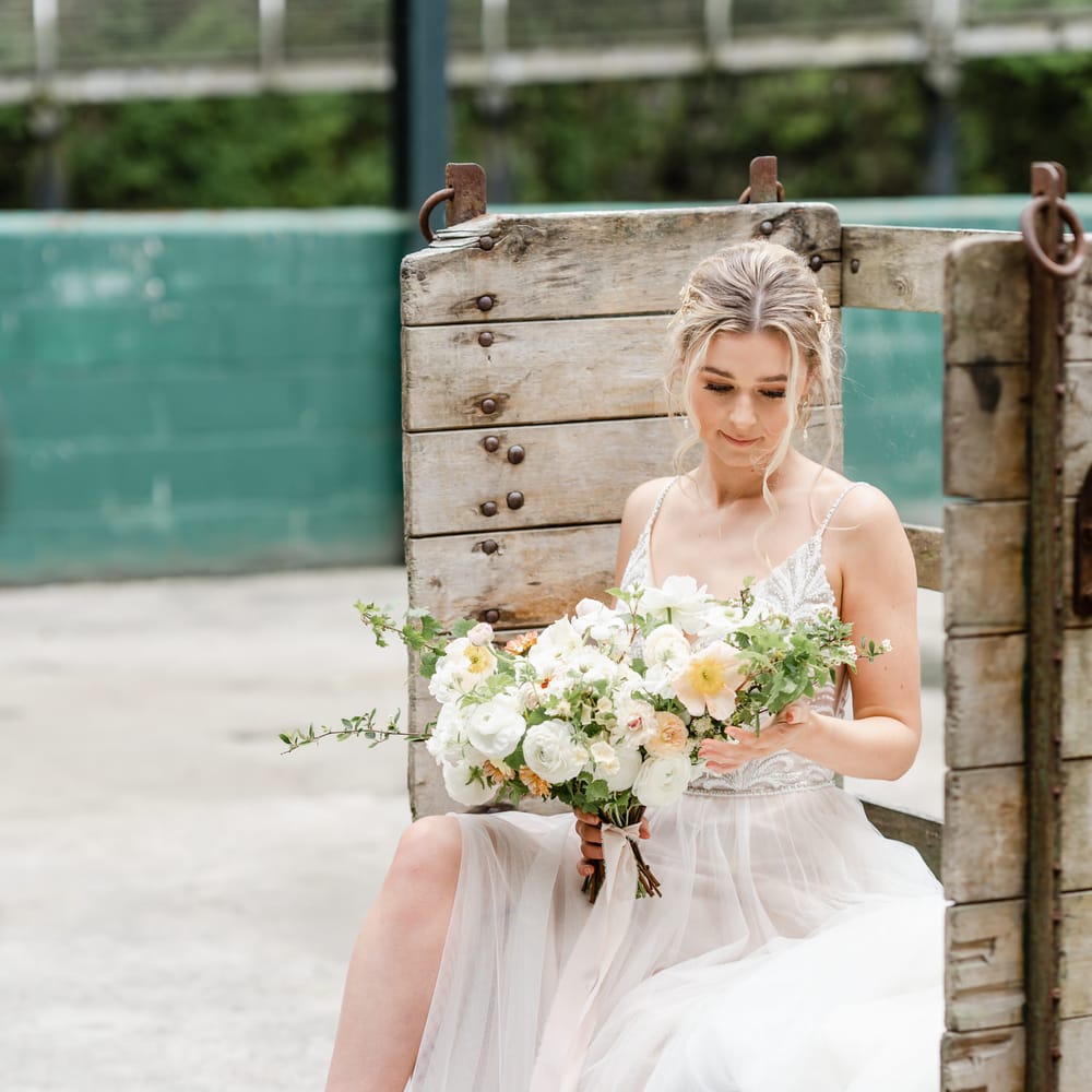 Bride in a tulle skirt wedding dress holding a romantic white wedding bouquet with anemone's, ranunculus and roses