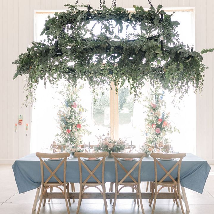 Intimate wedding reception table in front of the window at The White Barn with foliage hoop hanging installation and pastel wedding table decor 