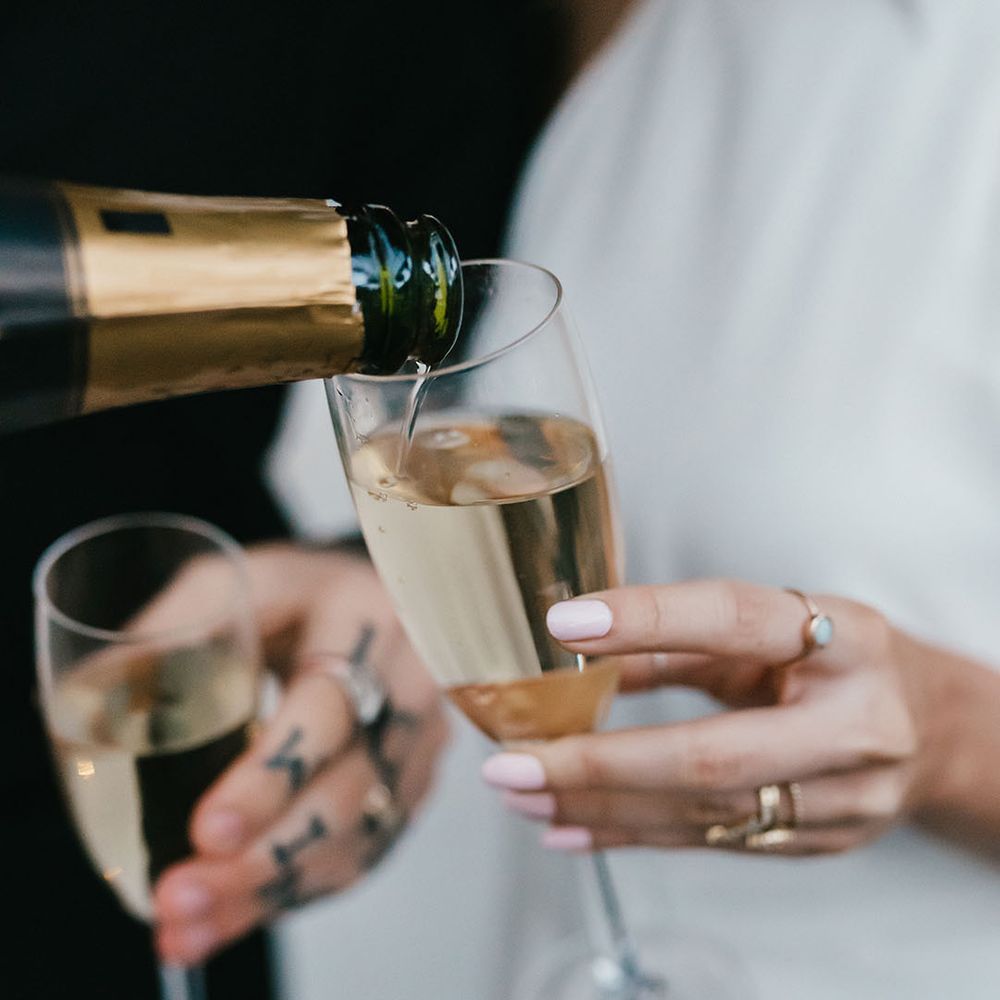 Bride with light pink wedding nails holding a flute champagne glass
