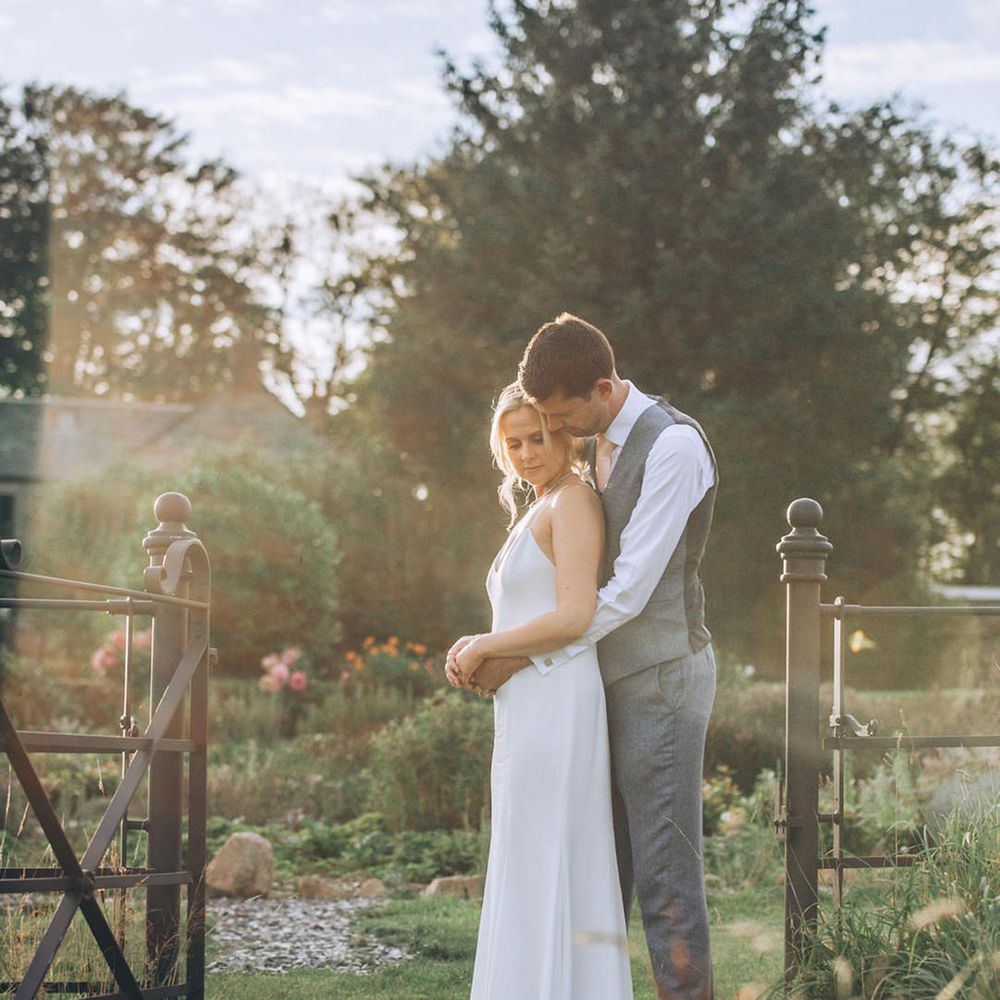 Bride and groom embrace in the gardens of Cornwall wedding venue
