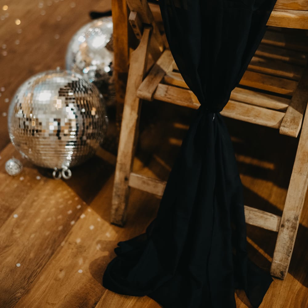 Wooden table and chair with black chair decor, disco balls and rustic tableware for Wellbeing Farm wedding in Lancashire