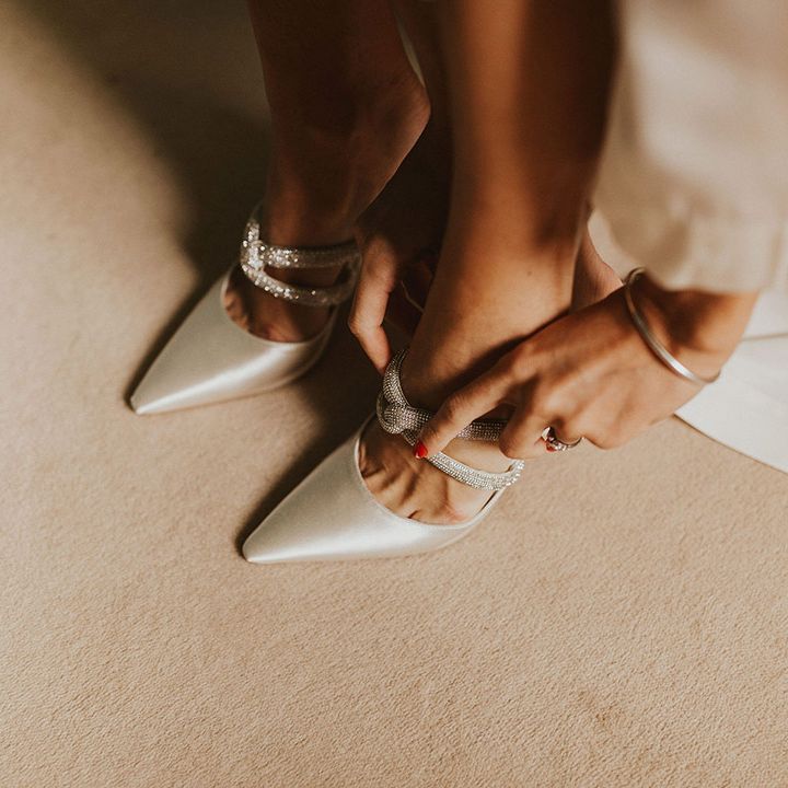 Bride puts on her wedding shoes with sparkling straps 
