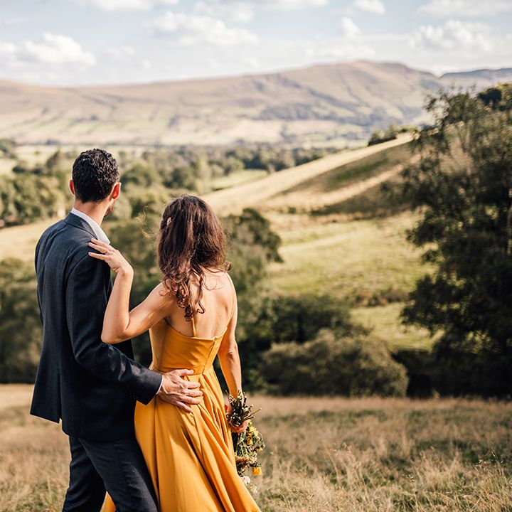 Bride & groom look across hills outdoors on their wedding day