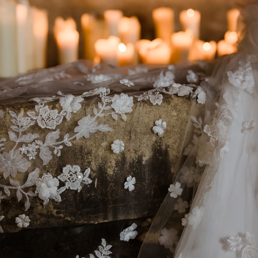 Close up of bride's stunning 3D lace veil with flowers in candlelight