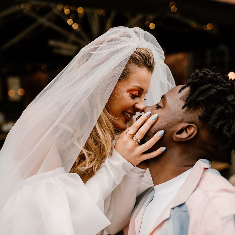 Bride with blue wedding nails holding her grooms face at fun London elopement 