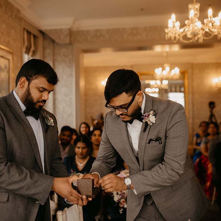 Ring bearer providing the rings to the groom in grey suit with black bow tie at Petersham Hotel 