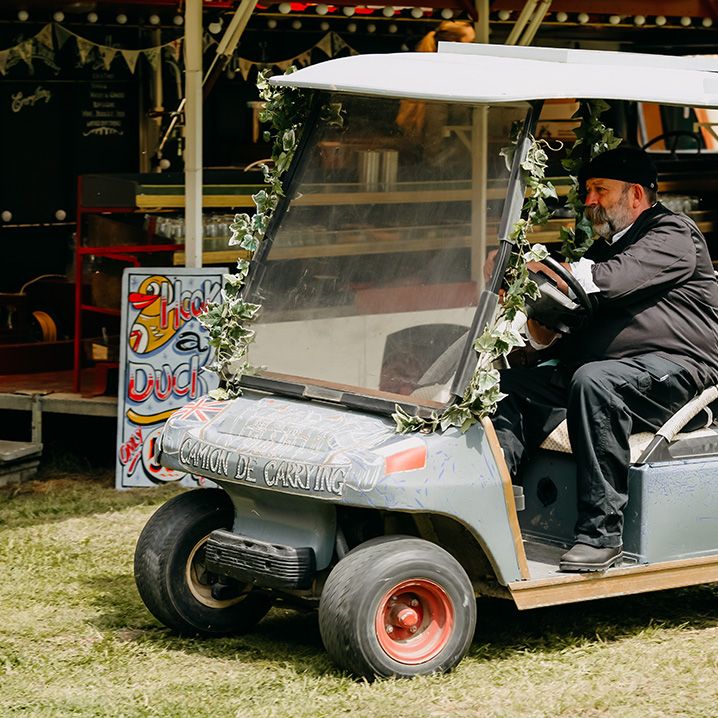 Wedding guest drives around on a golf buggy with foliage decor 