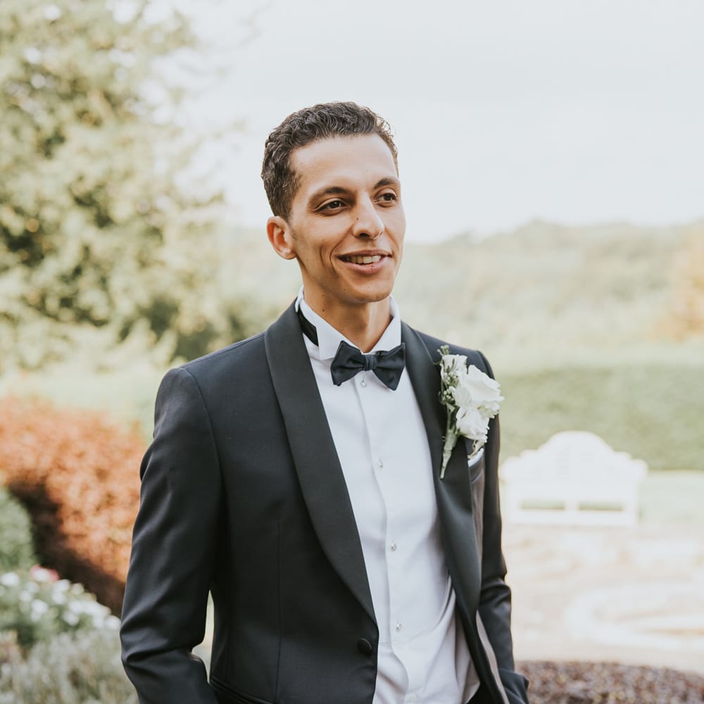 Groom in black tie for classic wedding with white rose buttonhole 