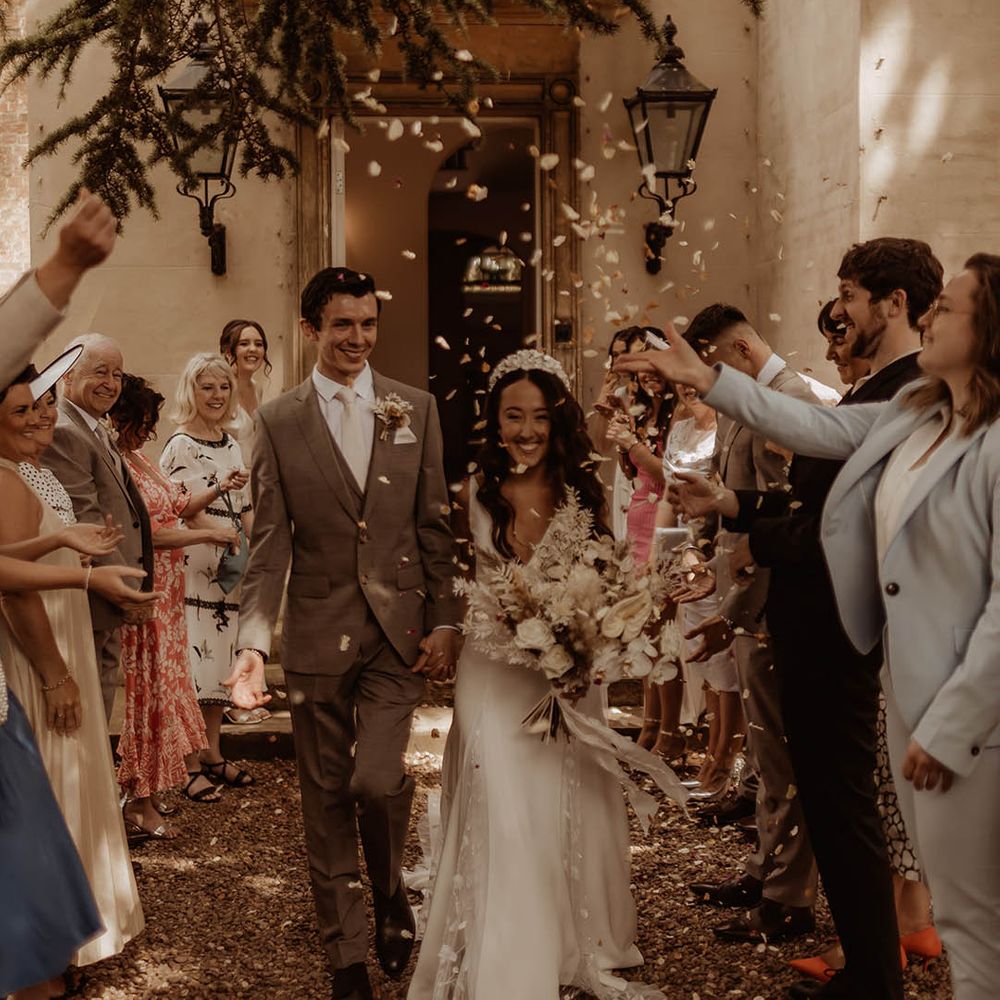 Wedding guests throw confetti over the bride and groom 