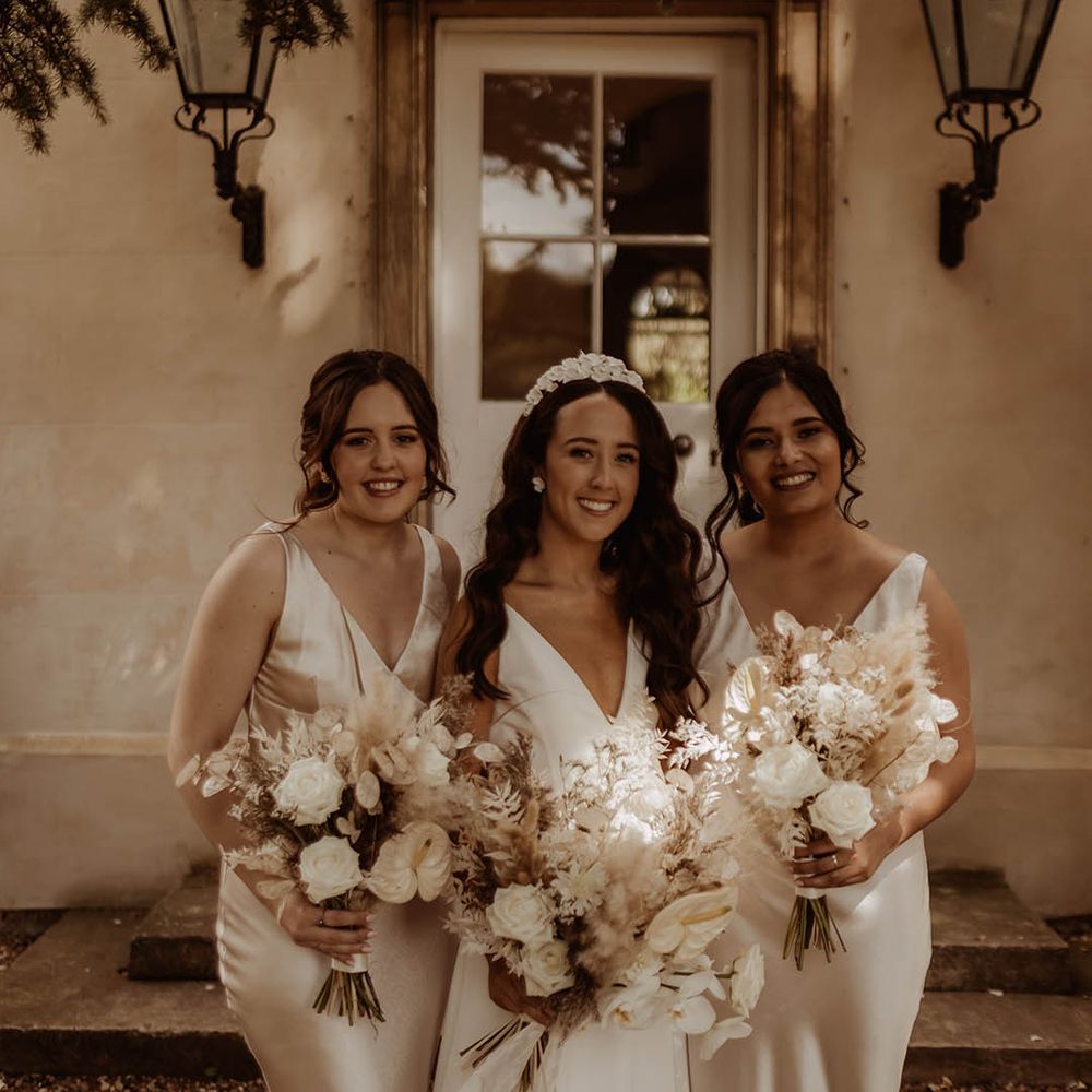 Bridesmaids in satin champagne gold dresses with bride in Alexandra Grecco wedding dress and their dried grass and white flower bouquets 