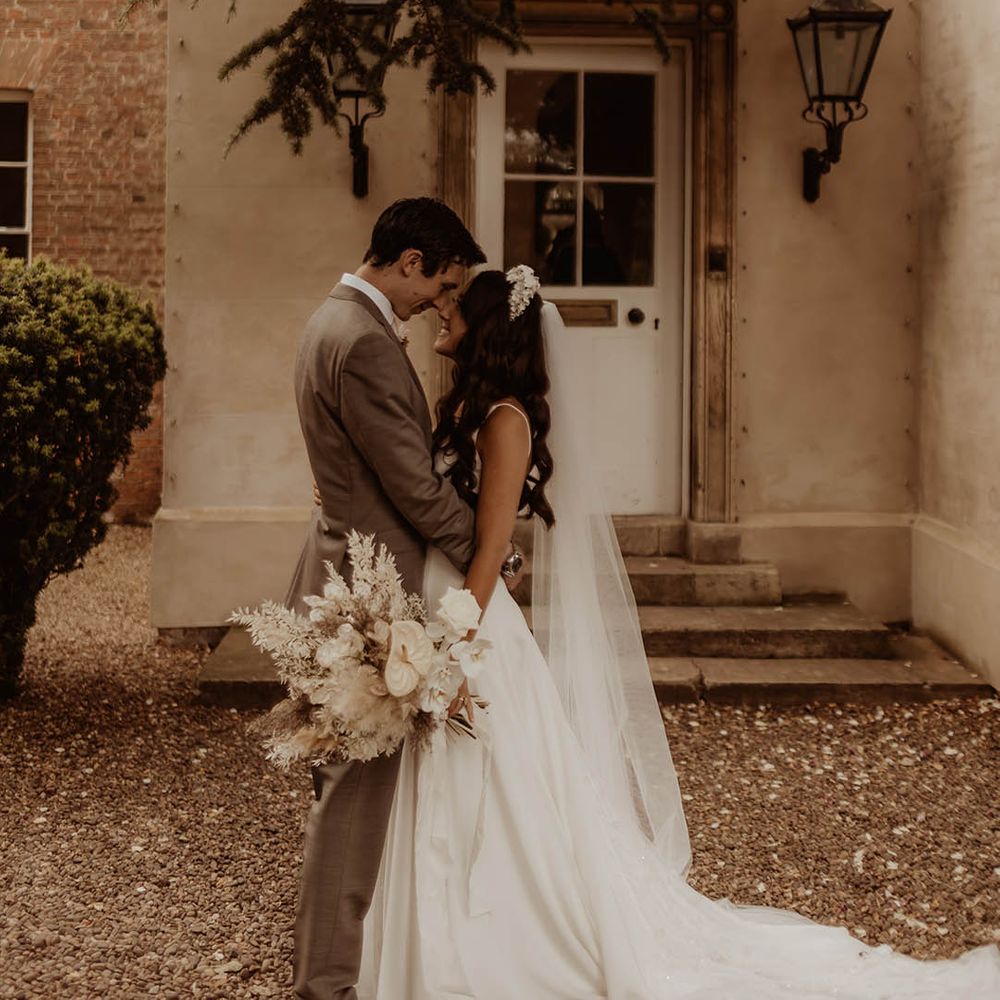 Groom in neutral wedding suit and bride in Alexandra Grecco v neck wedding dress with bridal headband 