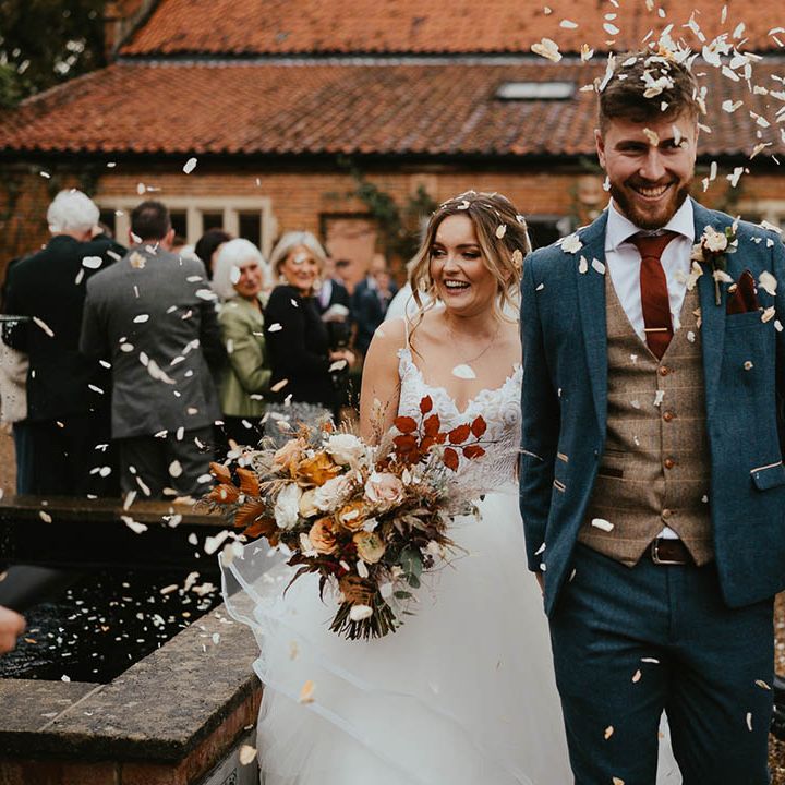 Bride and groom exit their ceremony to white confetti 