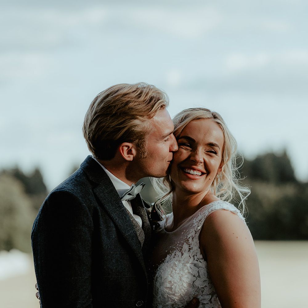 Bride in a princess wedding dress with silver wedding and engagement ring and groom in a tweed suit 