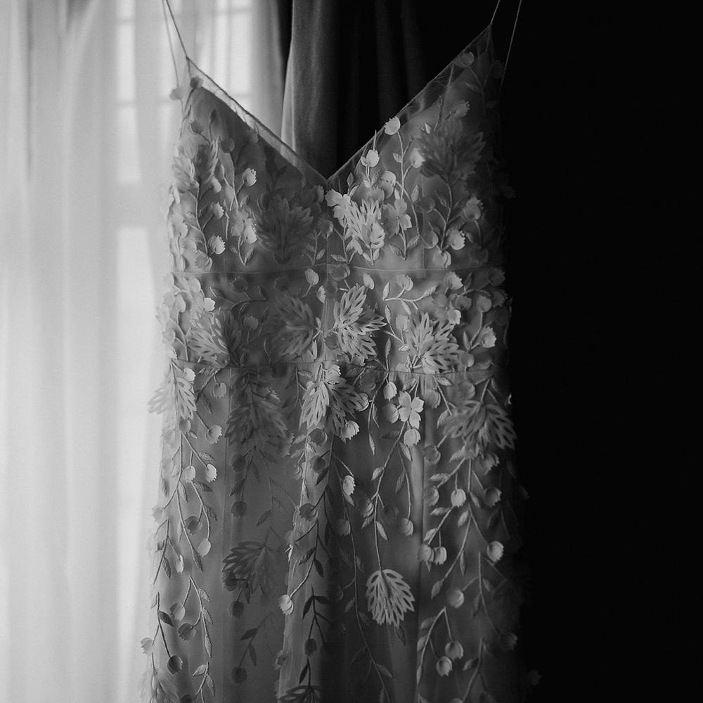 The bride's flower applique wedding dress is hung up ready for the bride 