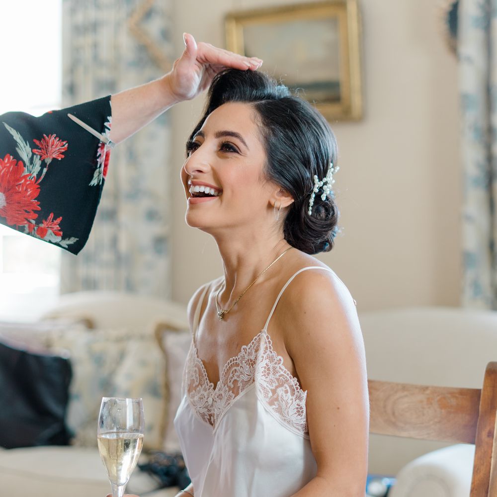 Bride wears her dark hair pinned back complete with pearl hair accessory and silk lace pyjamas 