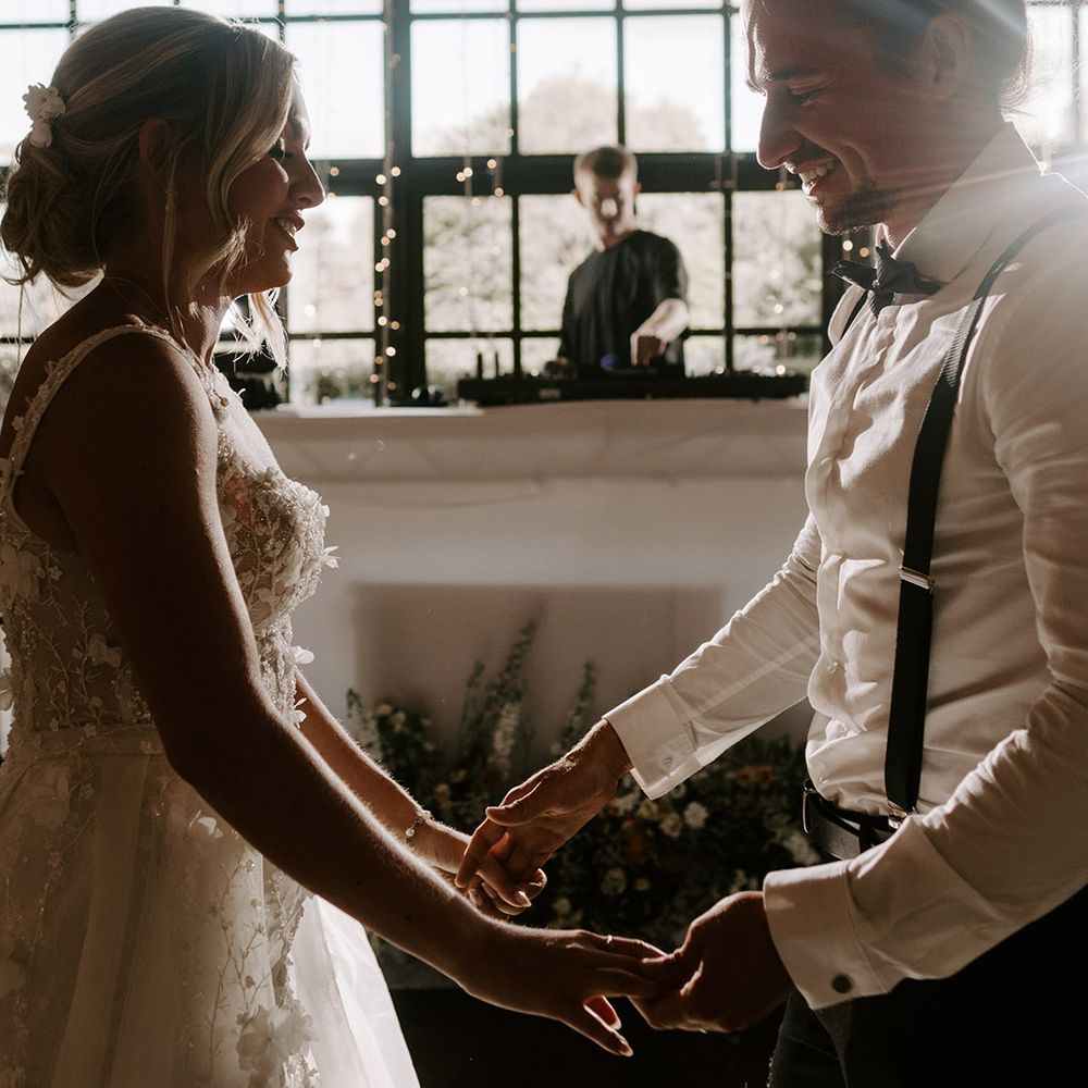 The bride and groom share their first dance together with the sun streaming in through the windows and the DJ playing on his decks 
