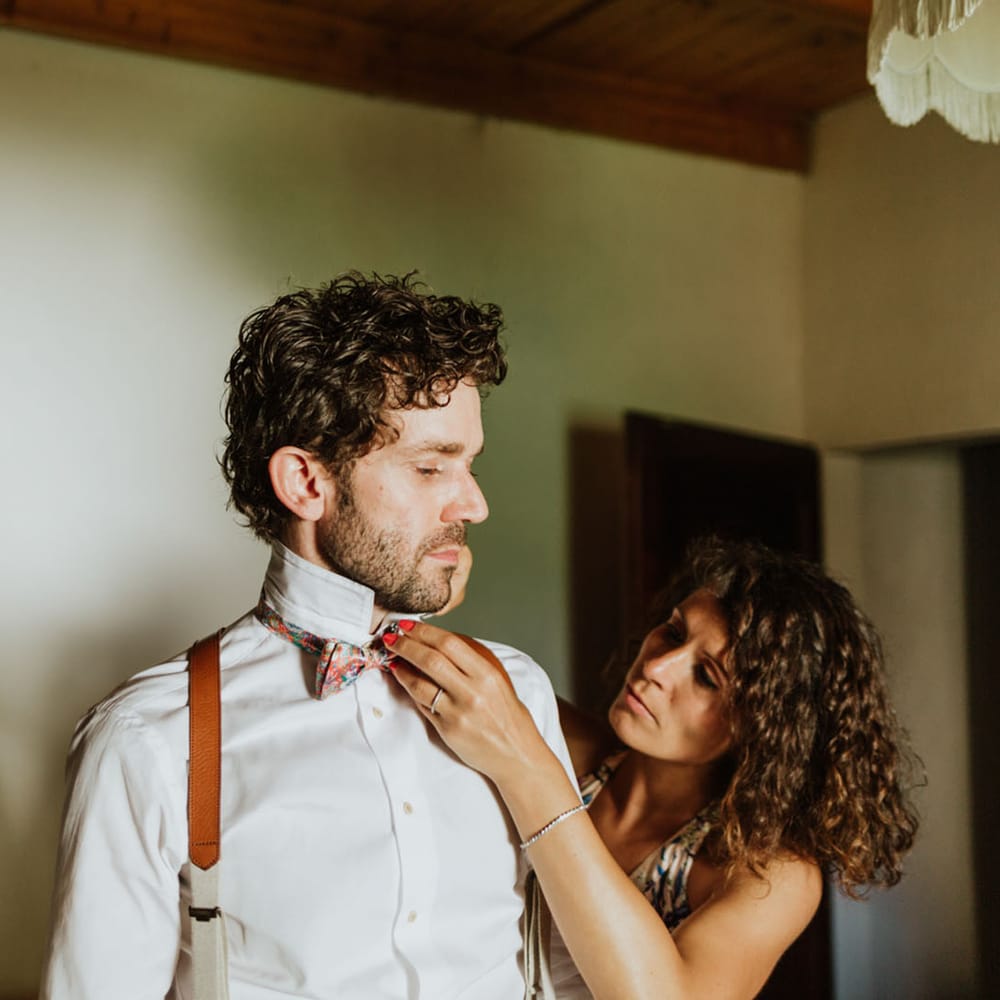 Groom getting ready wearing a white shirt with burnt orange braces