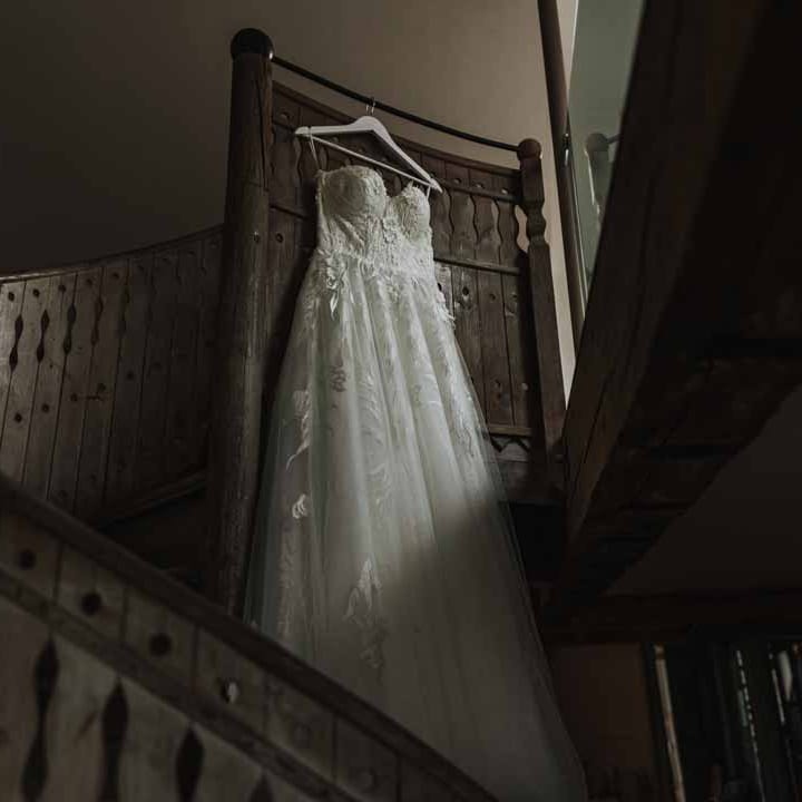 Sweetheart neckline lace wedding dress hanging on the spiral staircase at Lains Barn wedding venue 