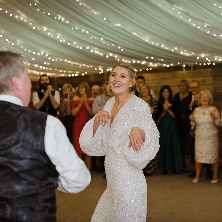 Bride in sparkly wedding reception dress dancing with her father for special father daughter dance 