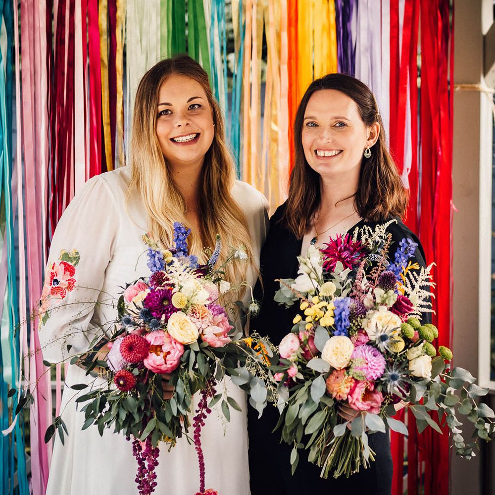 Rainbow wedding theme with colourful ribbon streamer decorations as photo backdrop at wedding 
