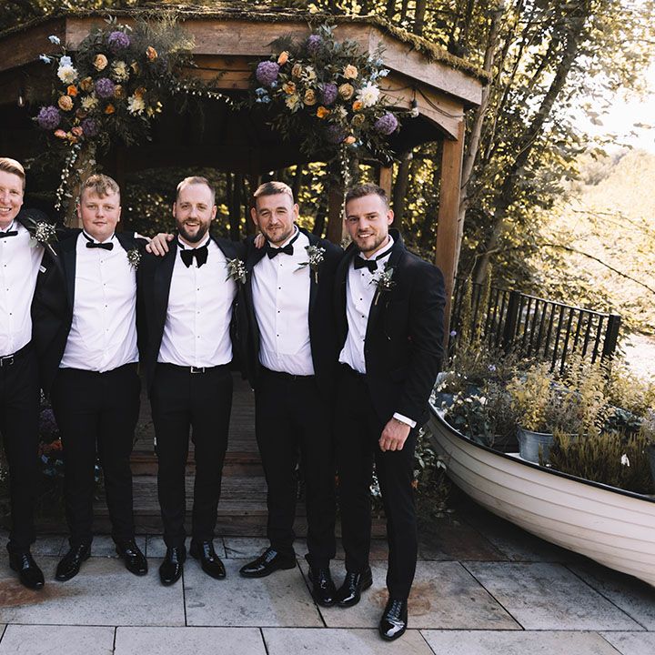 Groomsmen in black tuxedos for outdoor wedding 