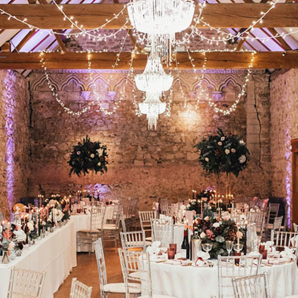 Notley Abbey winter wedding venue with chandeliers and fairy lights over the wedding tables decorated with tall table centrepieces 