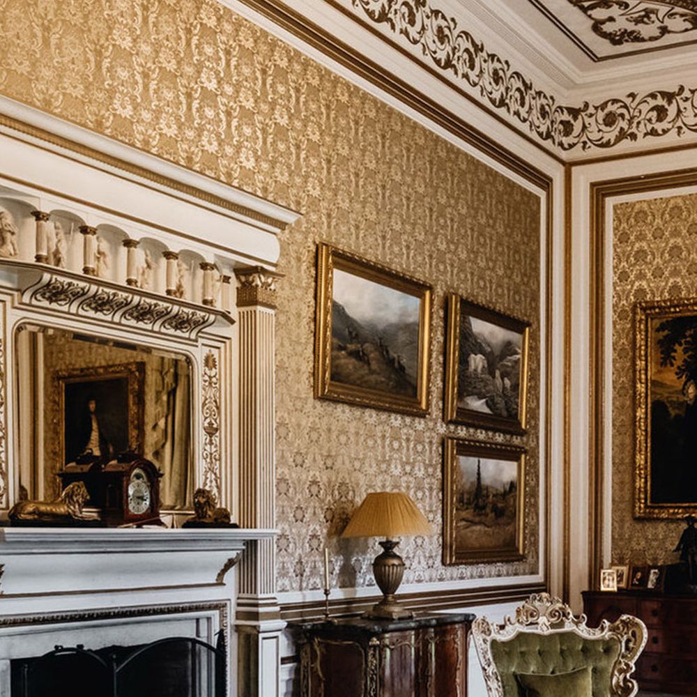 Traditional castle wedding venue with plush green velvet chairs, gold accents and classic paintings in the living room 