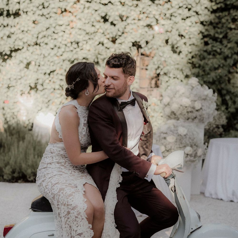 Bride and groom sit together on sage green moped 