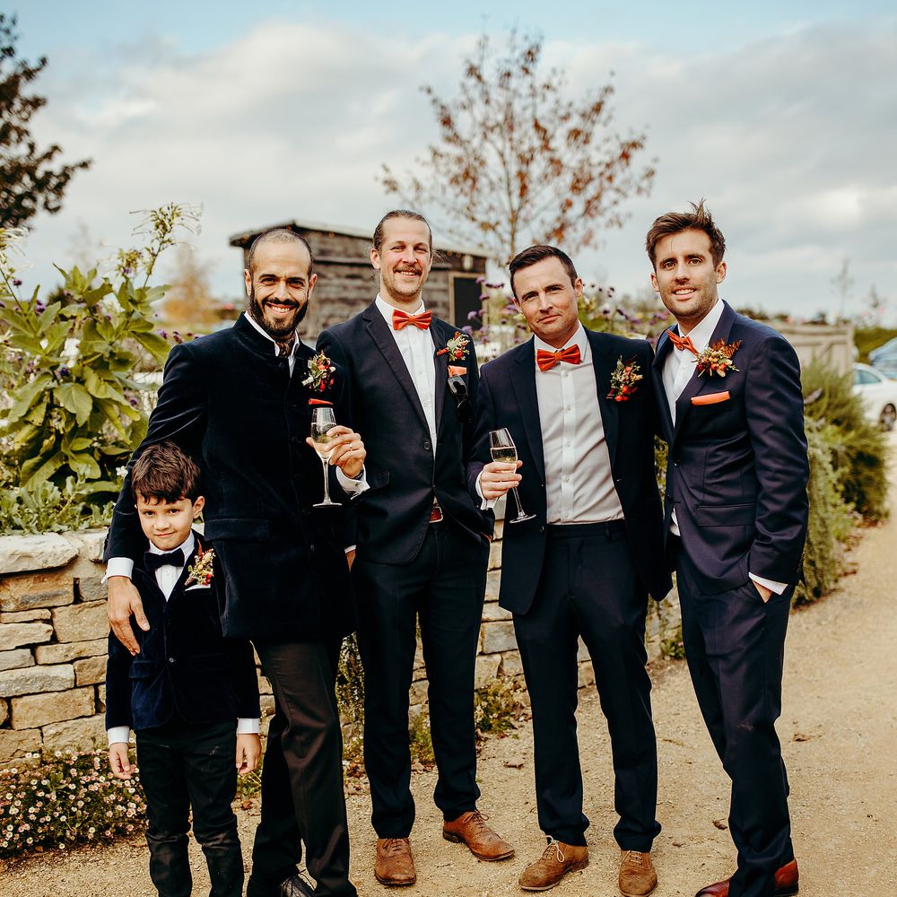 Groom stands with his groomsmen in deep blue suits
