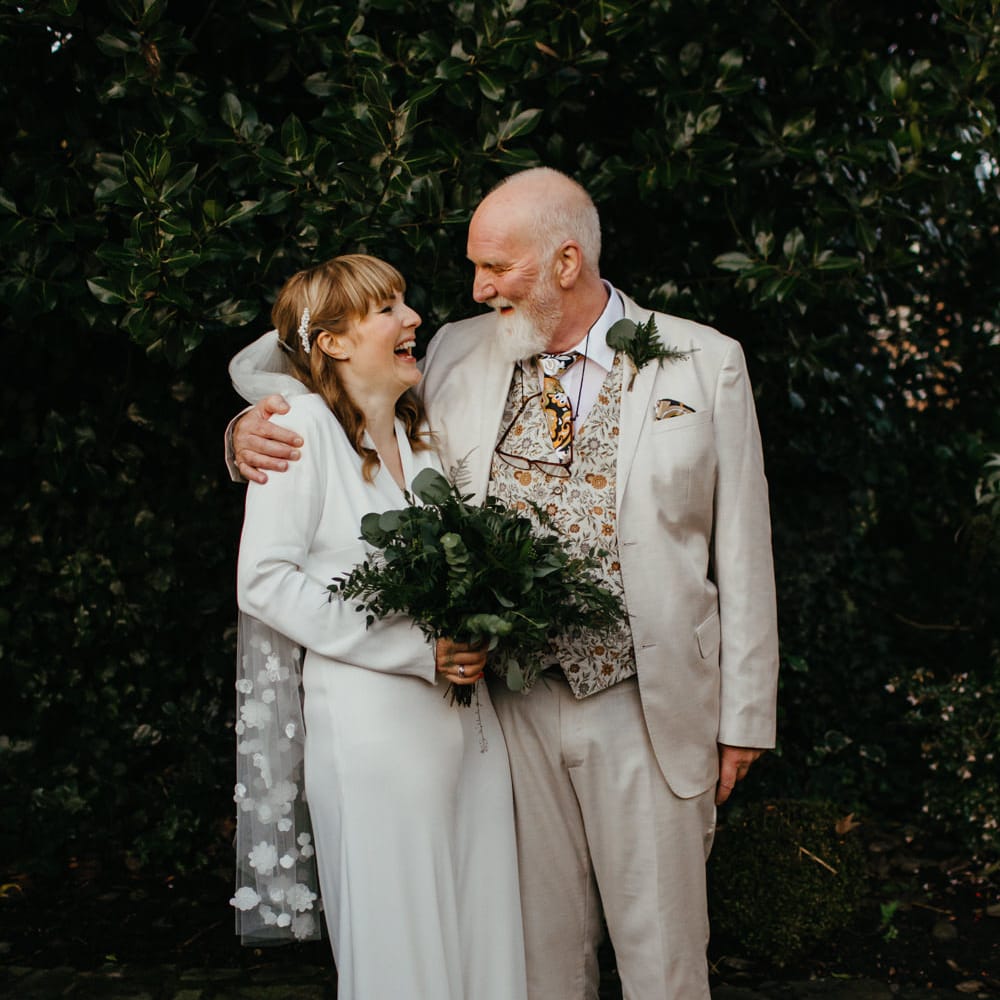 Father of the bride in a beige suit and floral waistcoat embracing his daughter 