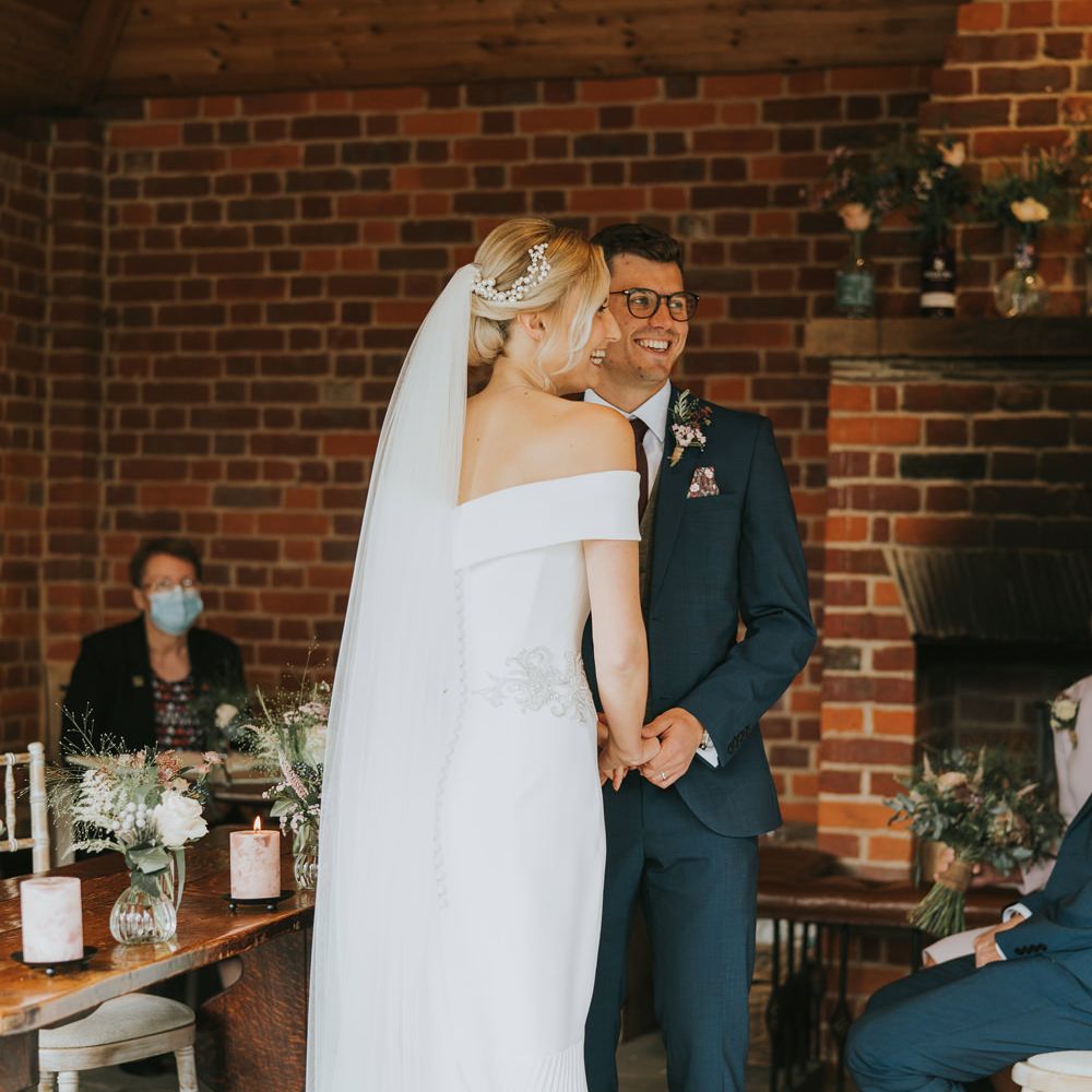 Bride wears fitted fishtail wedding gown with her groom during wedding ceremony