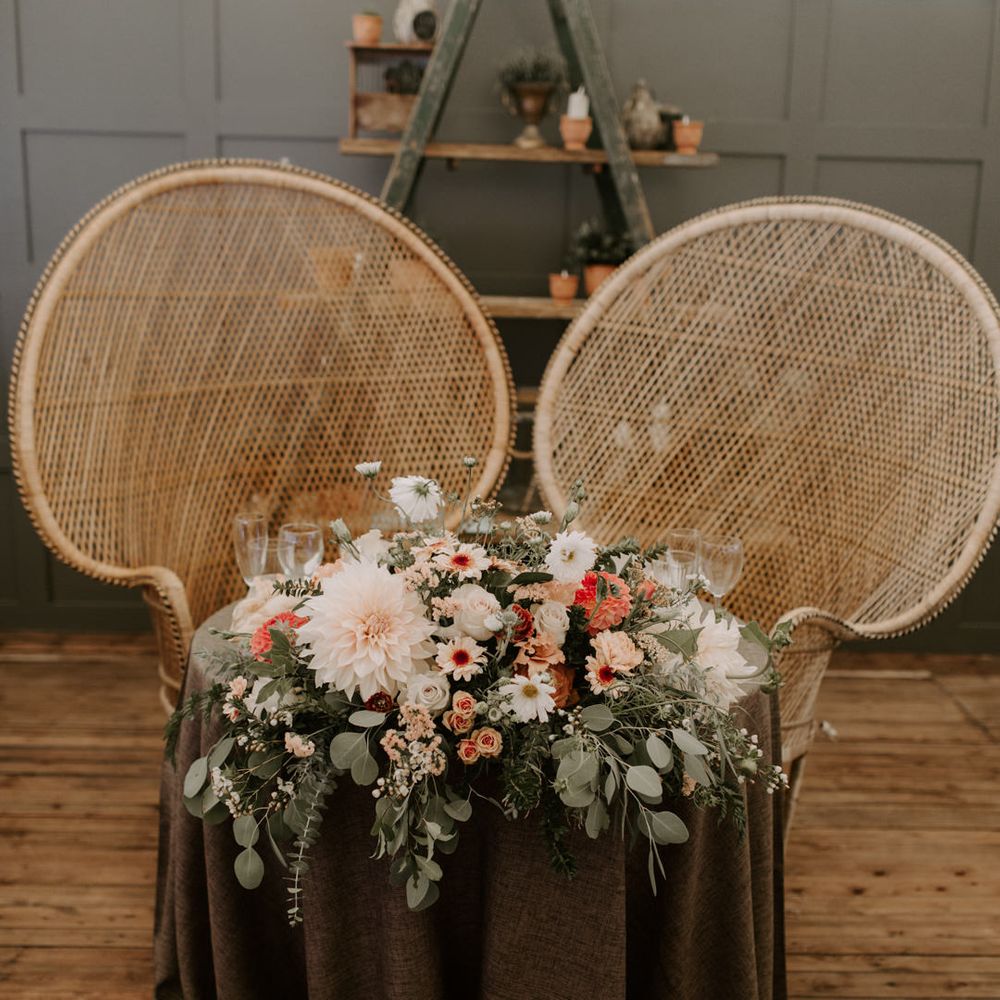 Sweetheart wedding table complete with wicker chairs and floral bouquet to the front