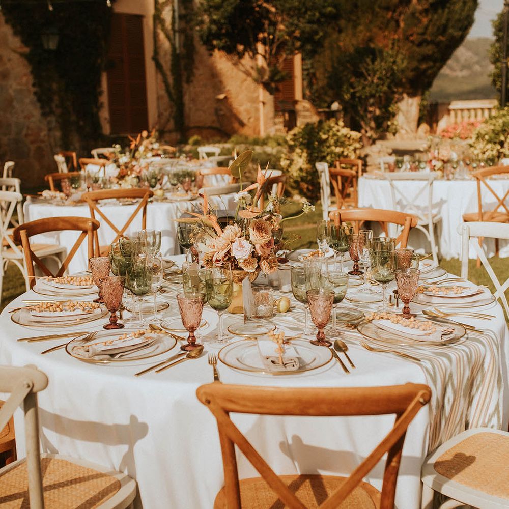Outdoor wedding reception complete with coloured glassware and floral bouquets