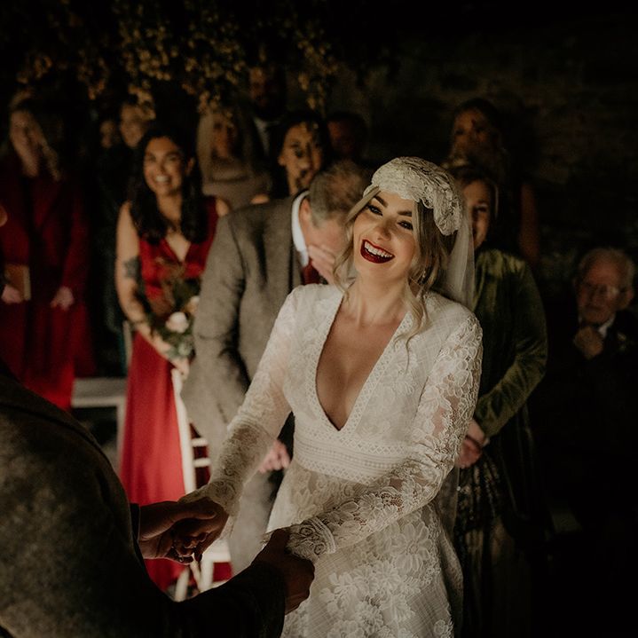 Happy bride in a lace wedding dress with plunging neckline and long sleeves 