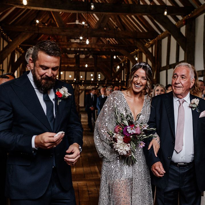 Father of the bride walking his daughter down the aisle in a grey sequin wedding dress at Tithe Barn, Loseley House wedding venue 
