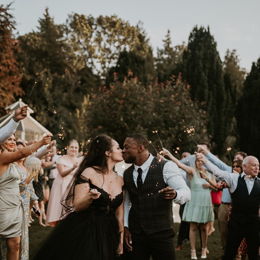 Bride & groom hold sparklers surrounded by wedding party 