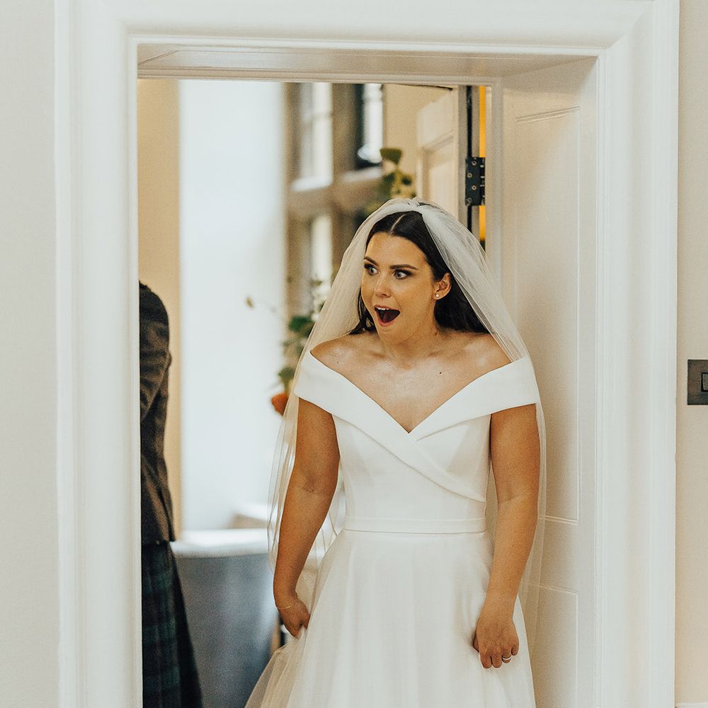 Bride in an off the shoulder Suzanne Neville wedding dress and long veil seeing her wedding reception for the first time 