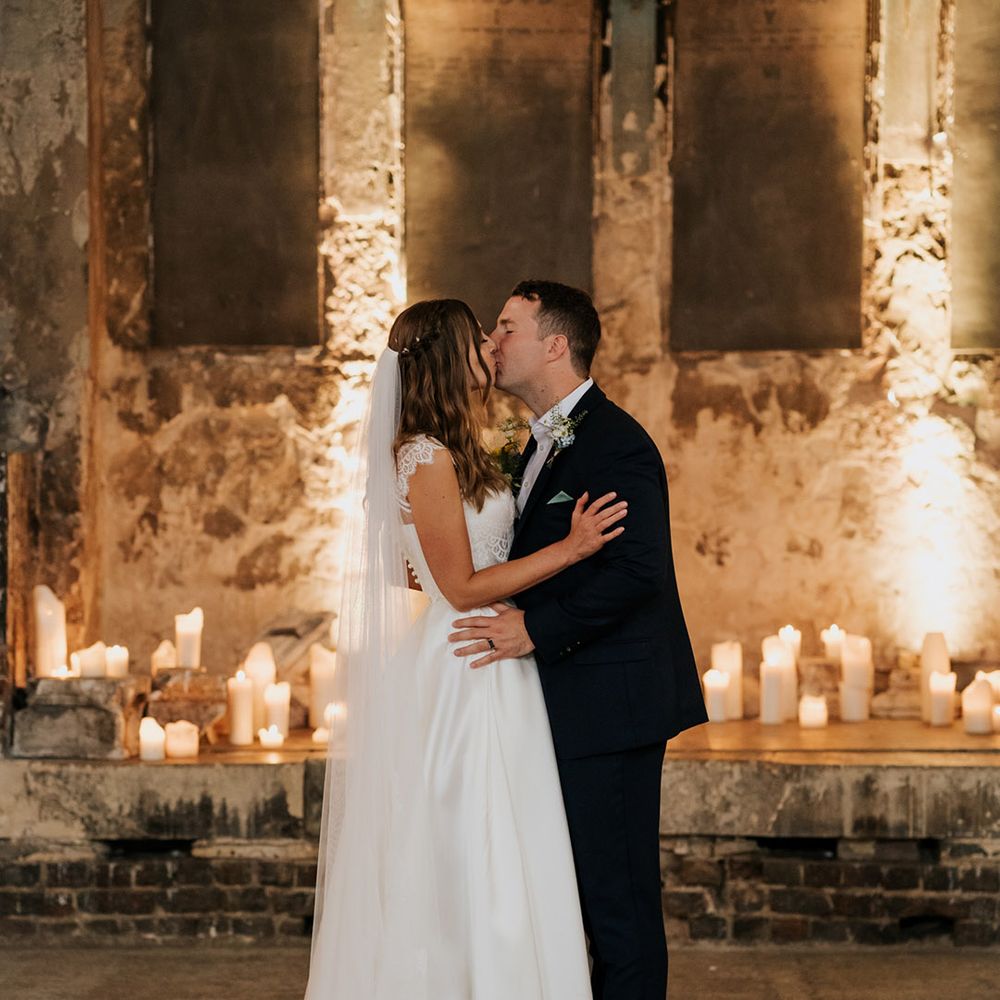 Bride and groom share an intimate kiss at candlelit wedding venue 