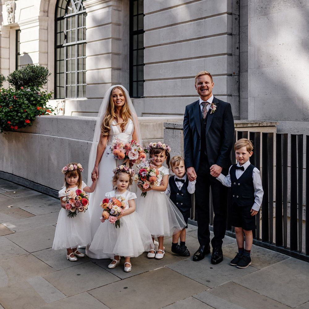 Bride and groom with their flower girls in white tulle skirt dress and page boys in navy shorts and waistcoats
