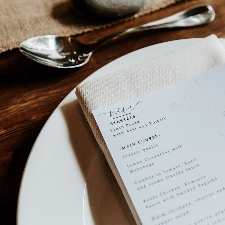 White menu card with flower design for wedding with silver cutlery and cream napkins