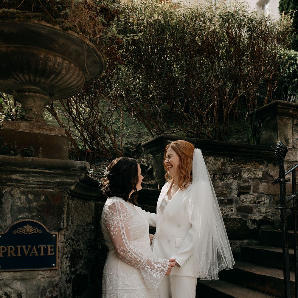 Brides laugh with one another outdoors during their Edinburgh wedding 
