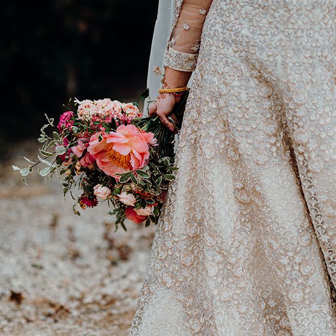 Bride carries bright floral bouquet for multicultural wedding at the Barn At Upcote 