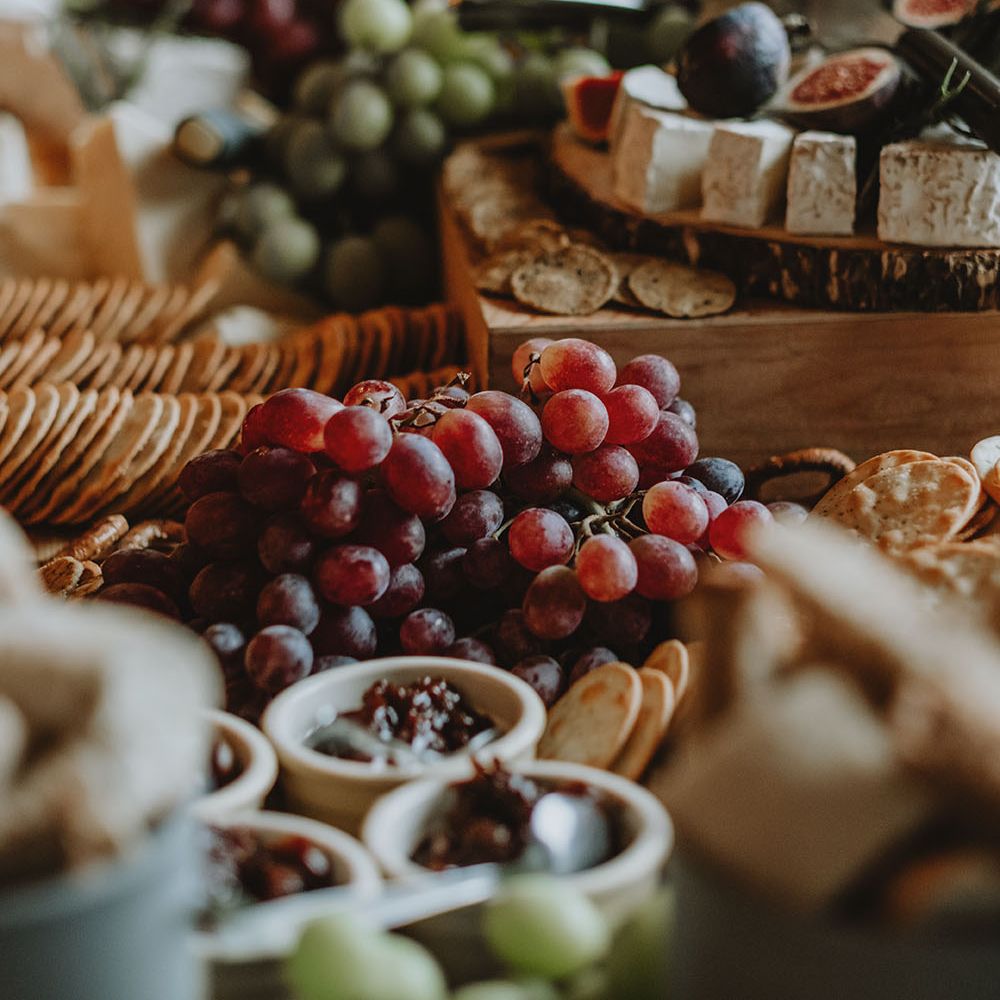 Wedding grazing table with cheese, figs, grapes and crackers on wooden boards 