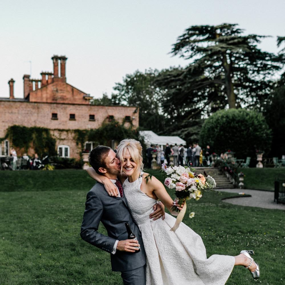 Bride in halter neck wedding dress and groom in dark suit at their country house wedding