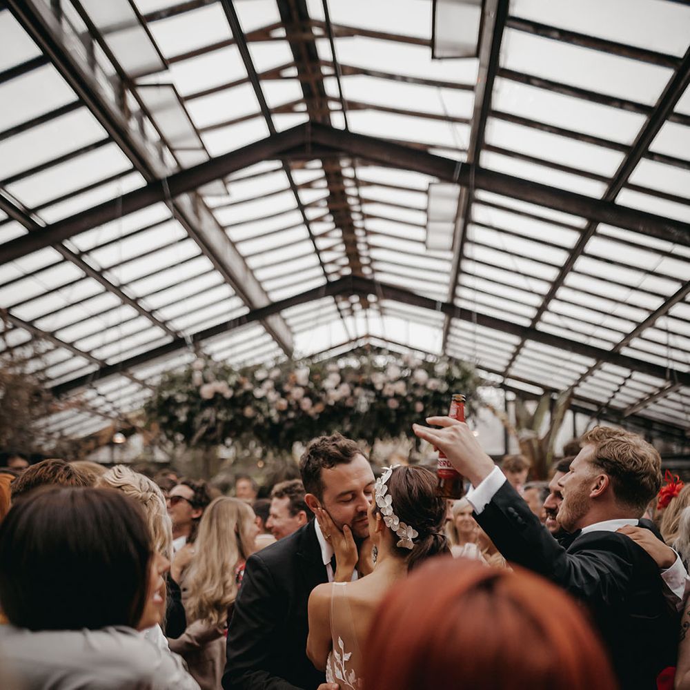Bride and groom lean in for a kiss as they dance with their guests for the reception 