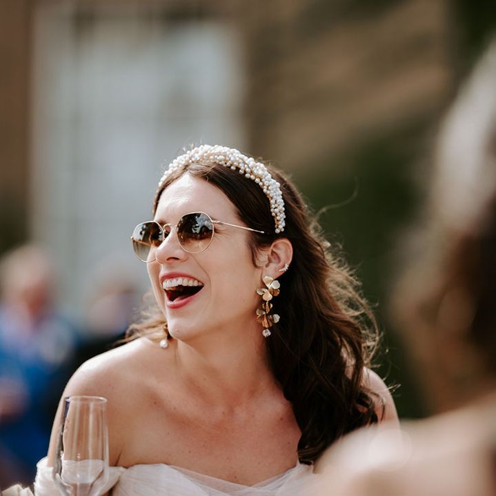 Bride wearing sunglasses with pearl headband and statement flower earrings 