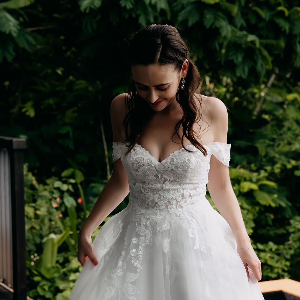 Bride in off the shoulder lace wedding dress with sweetheart neckline and lace floral details on the bodice and going down into the skirt
