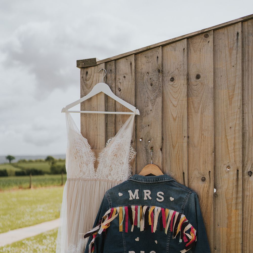 Personalised denim jacket complete with colourful fabric beside scalloped lace wedding dress