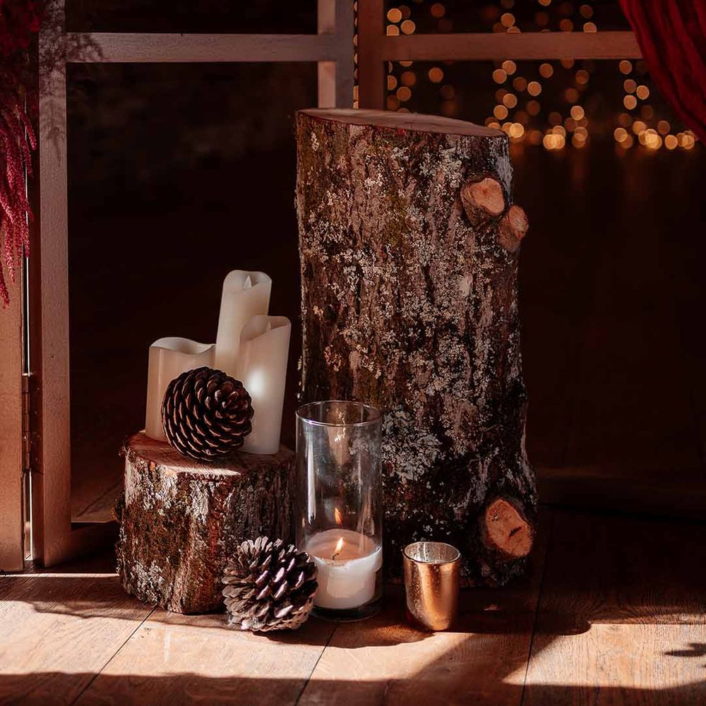 Two natural tree trunks with large pinecone decor, pillar candles, large glass candle jars and golden candle sticks